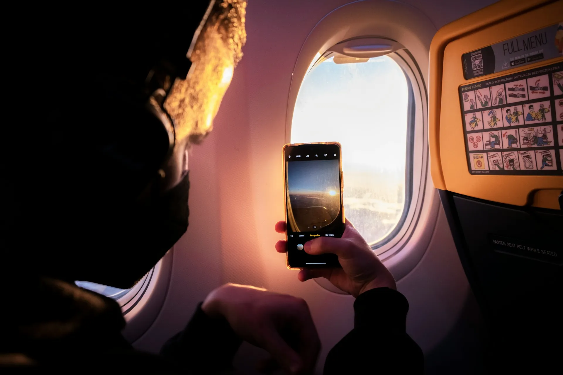A man taking a photo out of a plane window